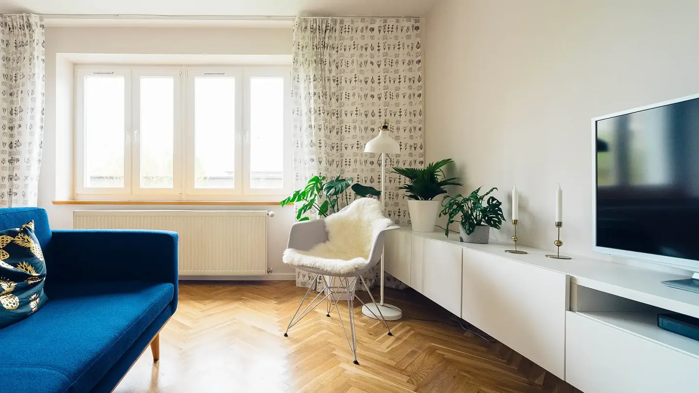 Salón de un piso reformado con suelo de espiga, ventana grande y radiador bajo el alféizar