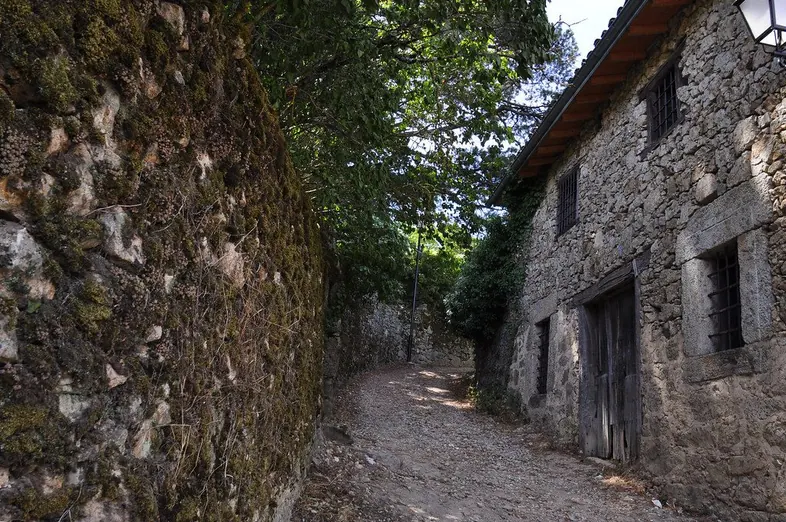 Callejón empedrado entre casas de piedra con balcones de madera, en un pueblo de montaña