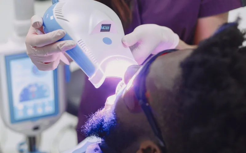 Lámpara de blanqueamiento sobre los dientes de una paciente