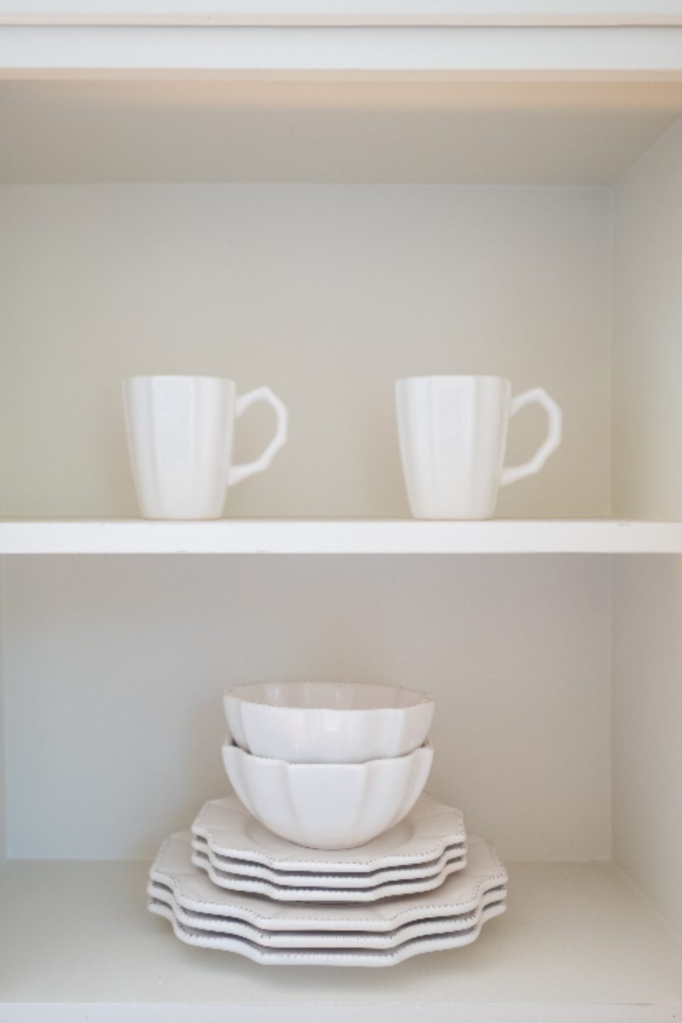 Estantería blanca con tazas de cerámica y un juego de boles apilados, fotografía de producto de Almadraque