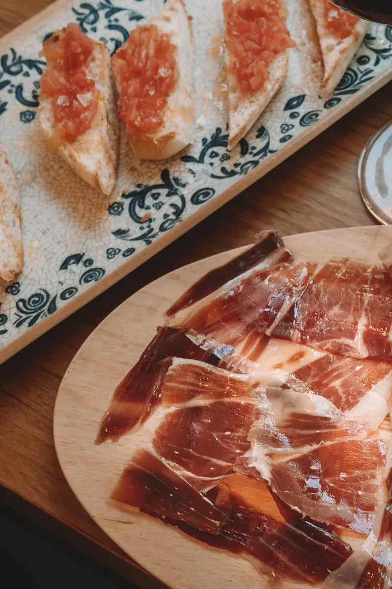 Lonchas de jamón ibérico junto a tostadas de pan con tomate