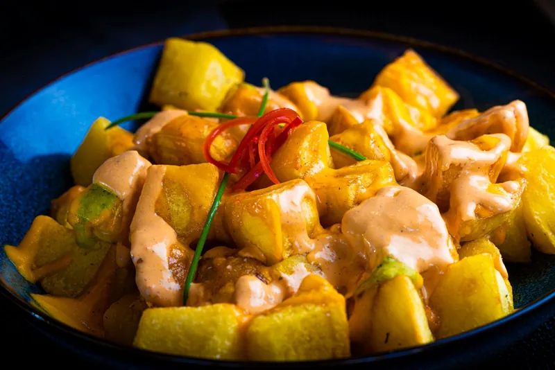 Patatas bravas con salsa en un cuenco azul